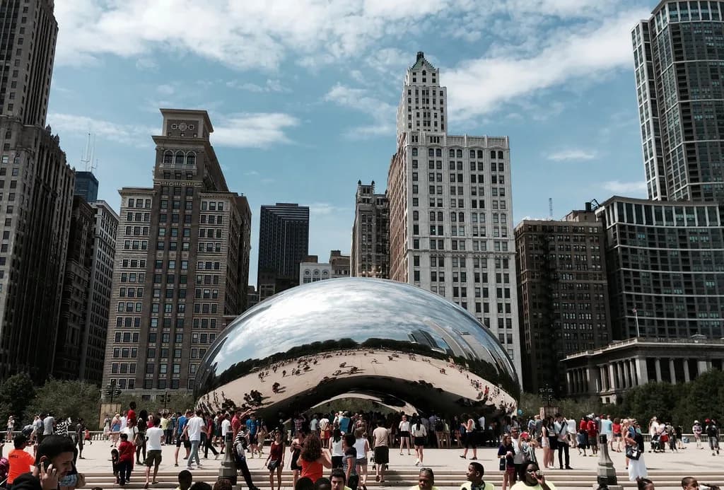Visitors gathered around the mirrored Cloud Gate sculpture in Millennium Park on a summer day