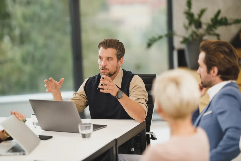 Colleagues talking through plans around a conference-room table before an offsite