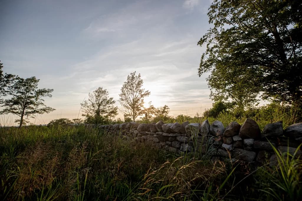 Stone wall crossing a quiet stretch of the Gettysburg battlefield at sunset