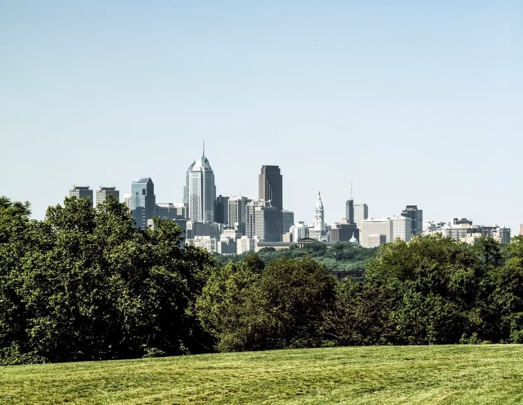 Philadelphia skyline rising beyond the green treetops of Fairmount Park in summer