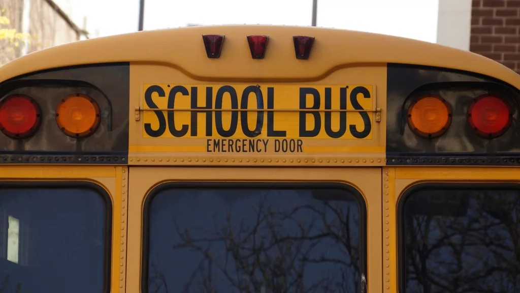 Rear of a yellow school bus with its School Bus sign and emergency-door lettering